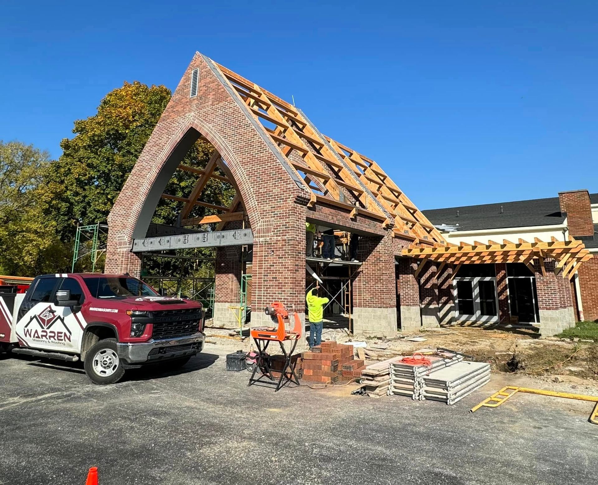 A construction site featuring a partially built brick structure with an exposed wooden frame roof in Indianapolis