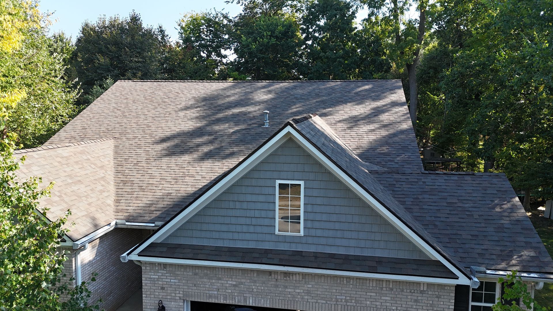 A high-angle view of a grey-shingled roof on a residential house in Indiana
