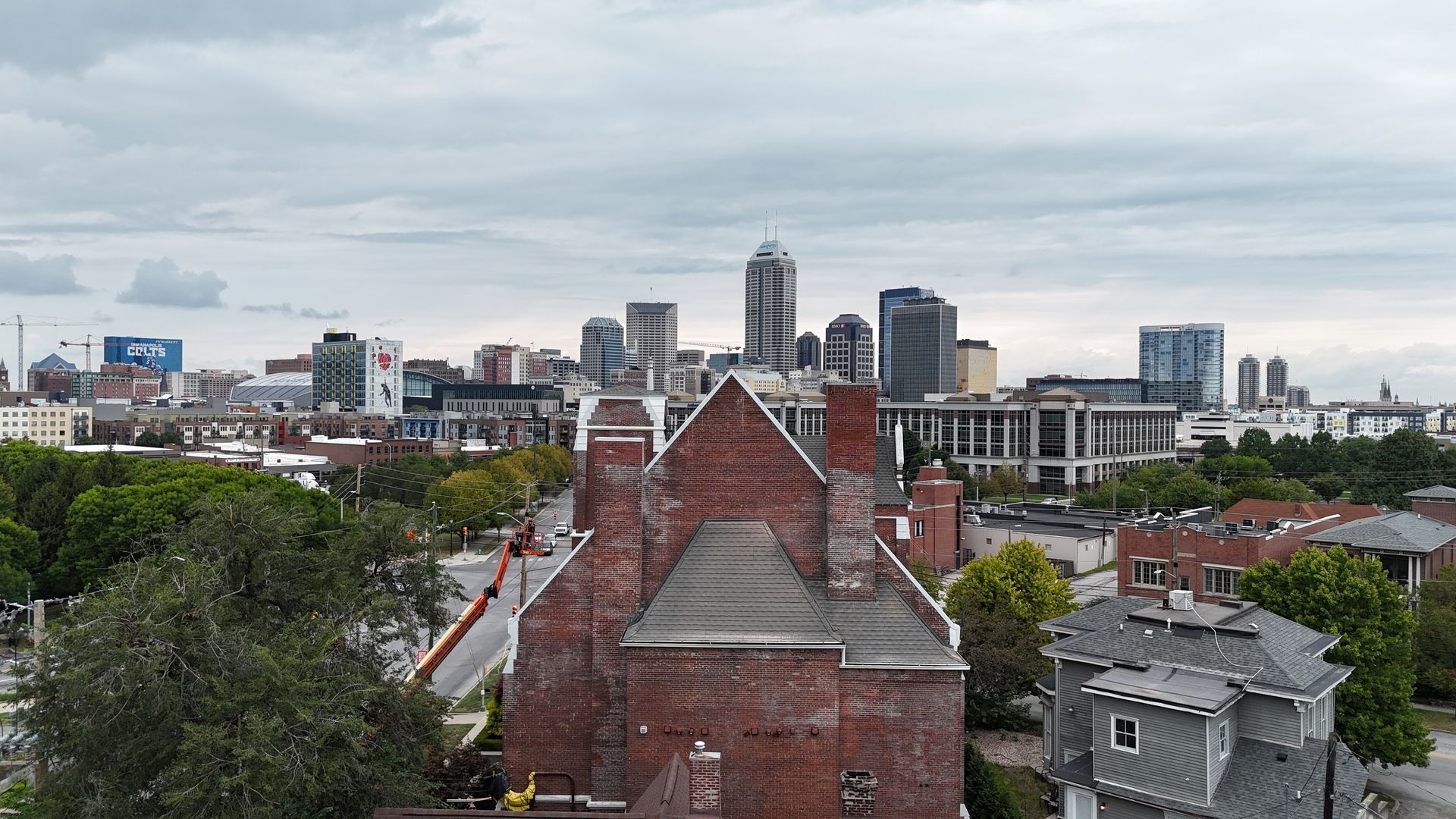 An elevated view of the Indianapolis skyline with a historic brick building in the foreground.